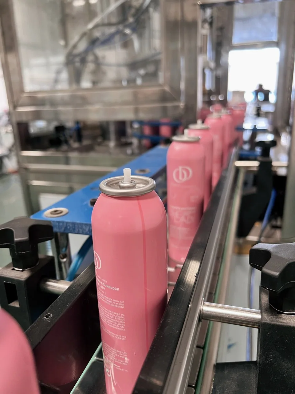 Pink aerosol cans on a conveyor, view 01