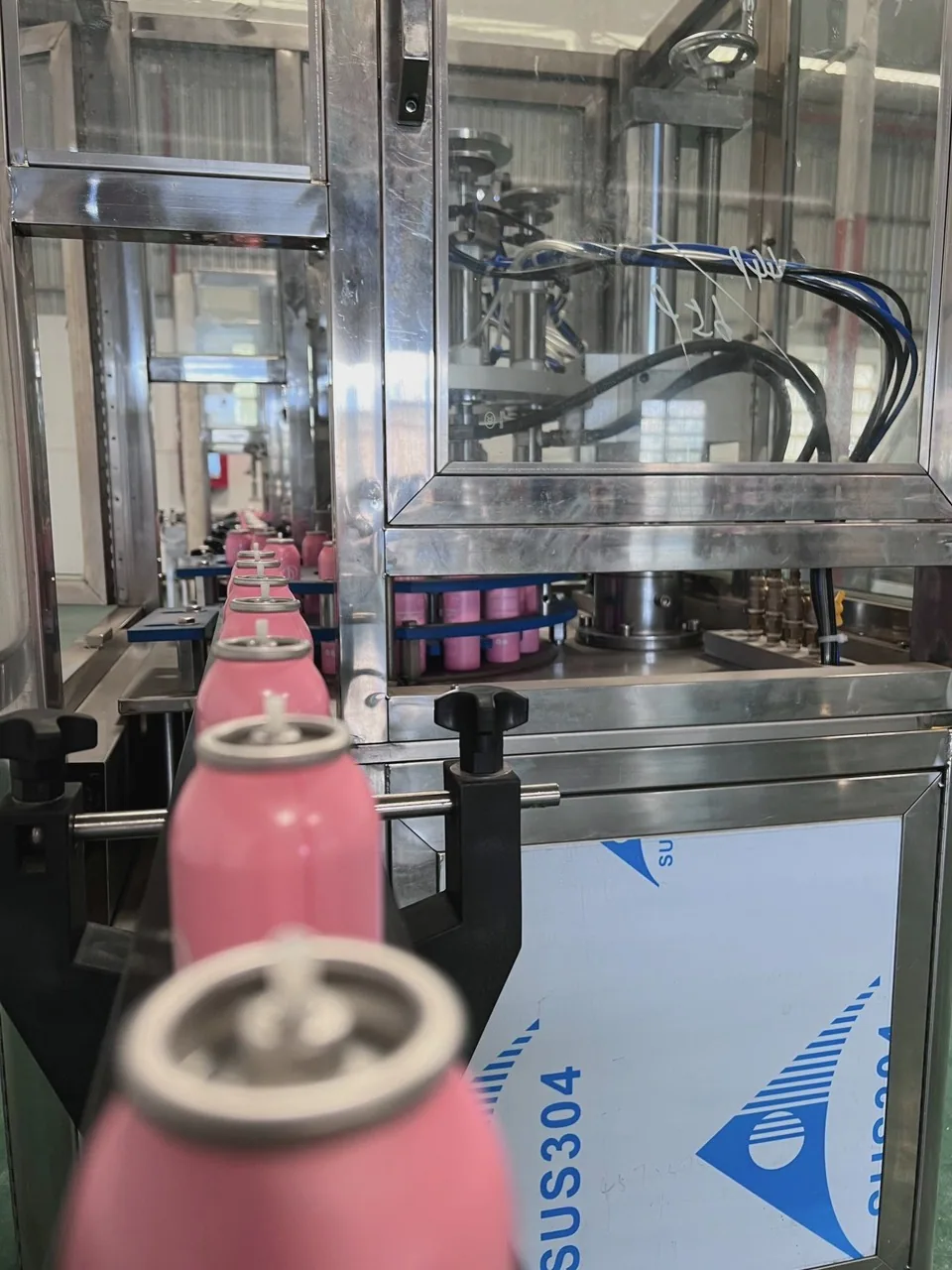 Pink aerosol cans on a conveyor, view 02